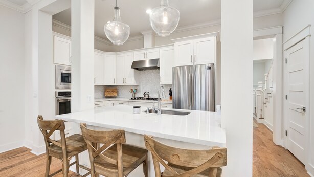 A modern kitchen with white cabinetry, stainless steel appliances, and a large island with bar stools. - Great summer deals! Golf cart & bikes included! Steps to pool, close to beach (Santa Rosa Beach)