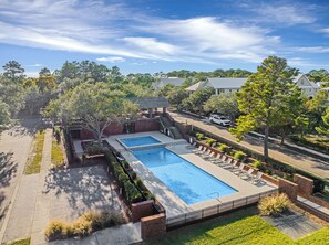 A rectangular pool with two separate sections, surrounded by a brick deck and a metal fence.