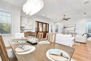 A modern dining area with a wooden table set for four, a white sofa, and a ceiling fan.