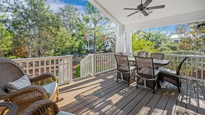 A covered outdoor deck with wicker furniture and a ceiling fan. - Great summer deals! Golf cart & bikes included! Steps to pool, close to beach (Santa Rosa Beach)
