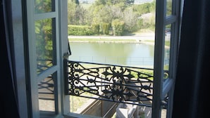 A room with a large window overlooking a body of water and greenery. - Canal View, superb gîte, Heated Pool near Carcassonne  next to Canal du Midi.  (Marseillette)