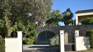 A gated entrance with a stone wall, a metal gate, and a small building in the background. - Canal View, superb gîte, Heated Pool near Carcassonne  next to Canal du Midi.  (Marseillette)