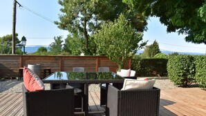 An outdoor patio with wicker furniture, a glass-top table, and a view of the sea. - Canal View, superb gîte, Heated Pool near Carcassonne  next to Canal du Midi.  (Marseillette)