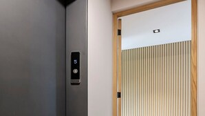 A modern elevator with a digital display, a wooden door frame, and a view of a room with a wooden floor and blinds. - w* | Outstanding 2BR with Balcony in Condesa (Ciudad de México)