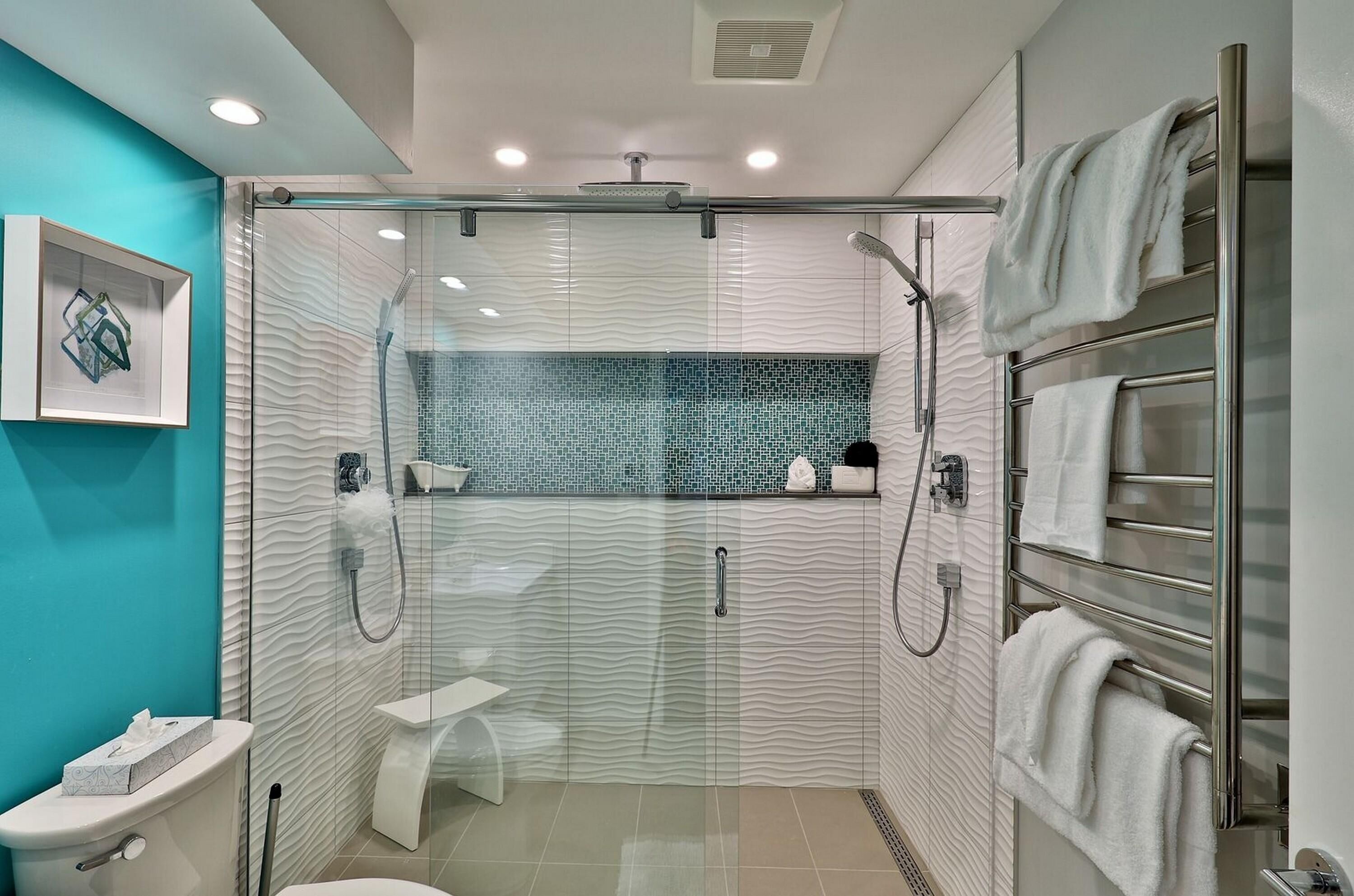 A modern bathroom with a glass-enclosed shower, a toilet, and a towel rack.