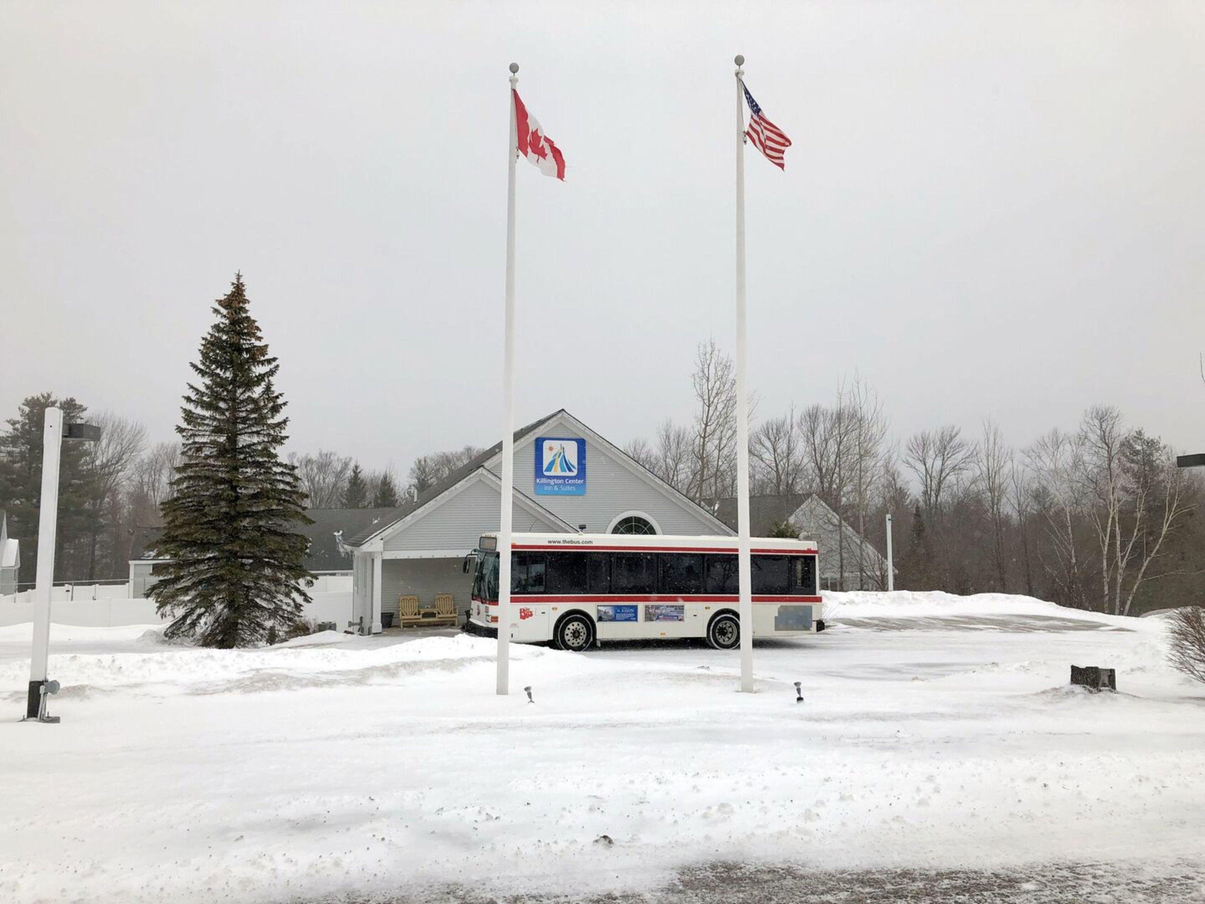 A bus stop with a building, two flags, and a snow-covered ground.