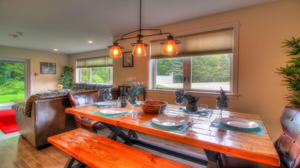 A dining area with a wooden table set for four, a bench, and a leather couch. - Killington Center Inn & Suites by Killington VR - 1 Bedrooms (Killington)