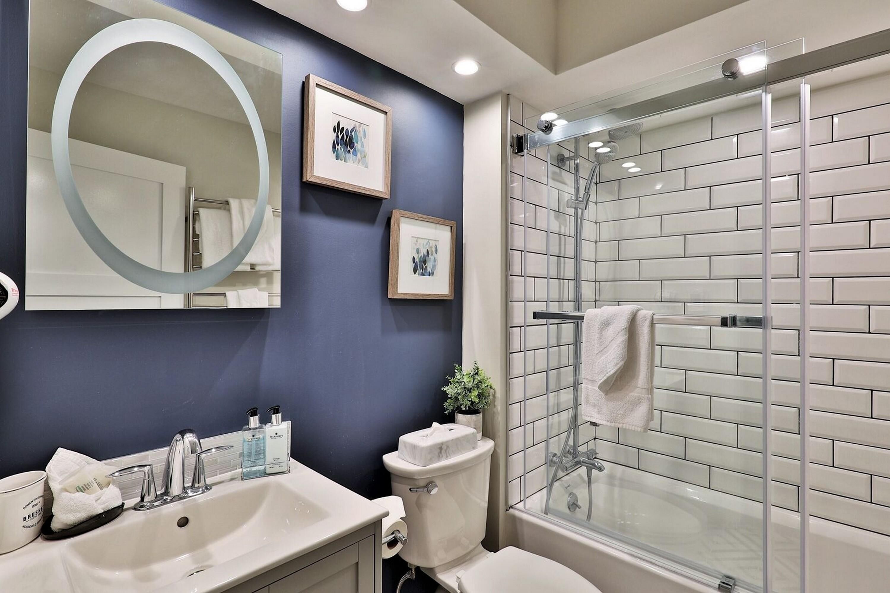 A modern bathroom with a glass shower, a large mirror, and a sink with toiletries.