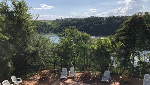 Zona de piscina con sillones de descanso y vista a un lago y colinas.