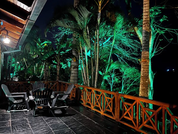 An outdoor seating area with chairs and a table, surrounded by a wooden railing and palm trees. - Costa del Sol Iguazu Nature & river (Puerto Iguazú)