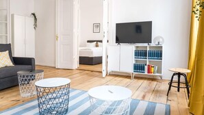 Un salon moderne comprenant un canapé, deux petites tables basses blanches, une bibliothèque et un téléviseur.