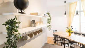 Un espace de salle à manger moderne avec une table et des chaises en bois, un globe terrestre posé sur une étagère et une fenêtre avec des rideaux.