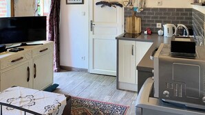 Eine rustikale Küche mit sichtbaren Balken, einer Chandelüster und einem Fernseher auf einem Schrank.