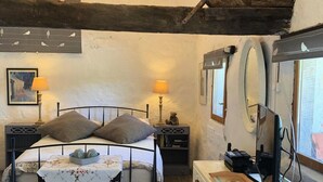 Ein rustikales Schlafzimmer mit Bett, Nachttischlampen, Teppich, Kommode und Spiegel.