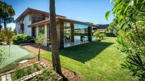 Ein modernes Haus mit Swimmingpool, einem gepflegten Rasen und einer Terrassenfläche.