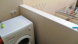 Un espacio lavandería pequeño con lavadora, tendedero y una ventana.