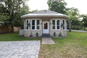 Stylish single-story house with a gabled roof and symmetrical facade, featuring a front entrance with a white door and two windows.