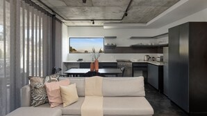 A modern kitchen with a built-in stove, a dining area with a table and chairs, and a sofa with a throw blanket. - Contemporary 3-Bedroom in Bo-Kaap | Views and Pool (Cape Town)