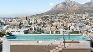 A swimming pool with a 'No Diving' sign, surrounded by a cityscape with buildings and mountains in the background. - Contemporary 3-Bedroom in Bo-Kaap | Views and Pool (Cape Town)