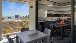 A modern kitchen with a dining area, a view of the city, and a balcony with a railing and plants. - Contemporary 3-Bedroom in Bo-Kaap | Views and Pool (Cape Town)