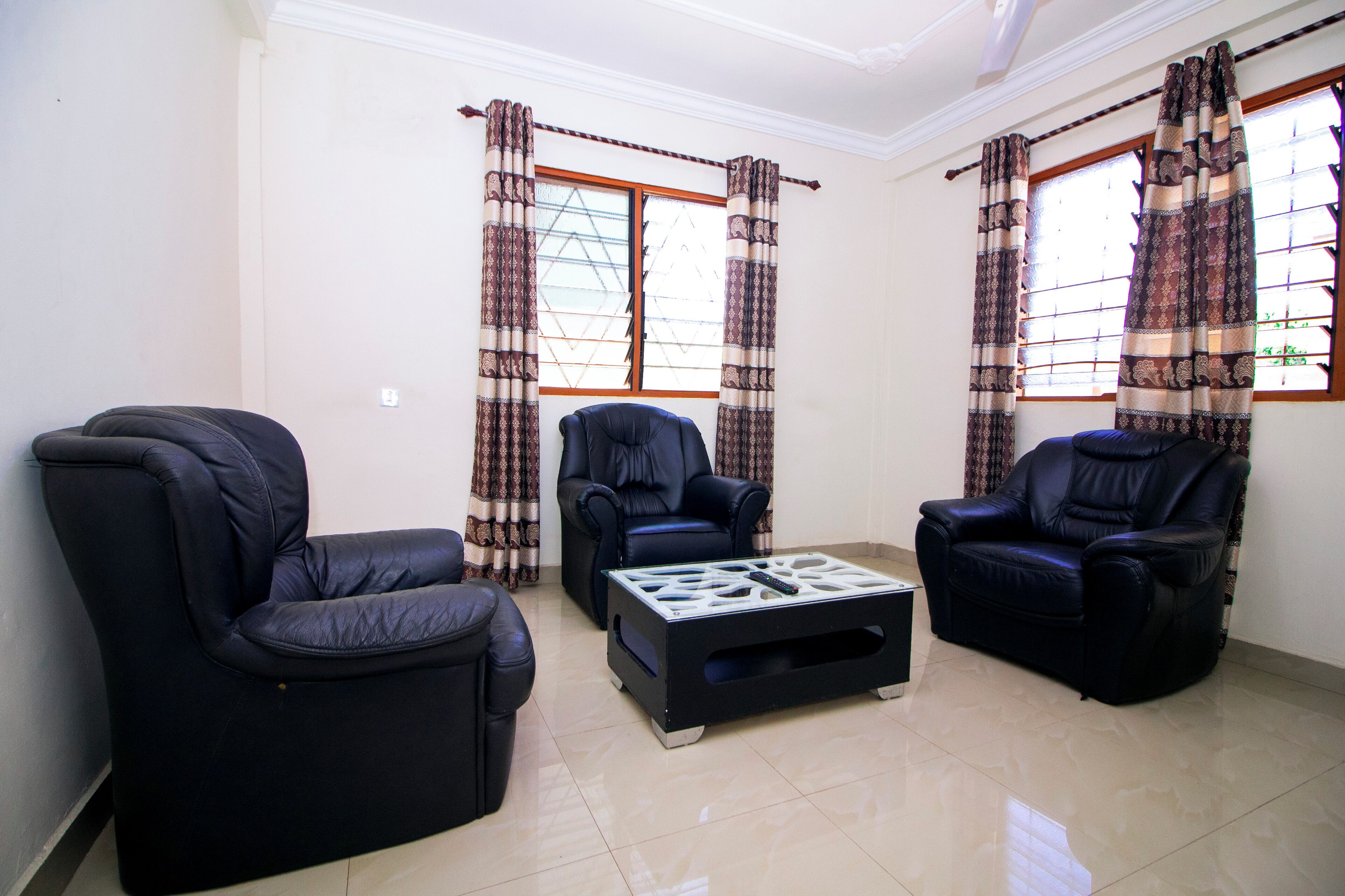 A living room with three black leather sofas and a coffee table.
