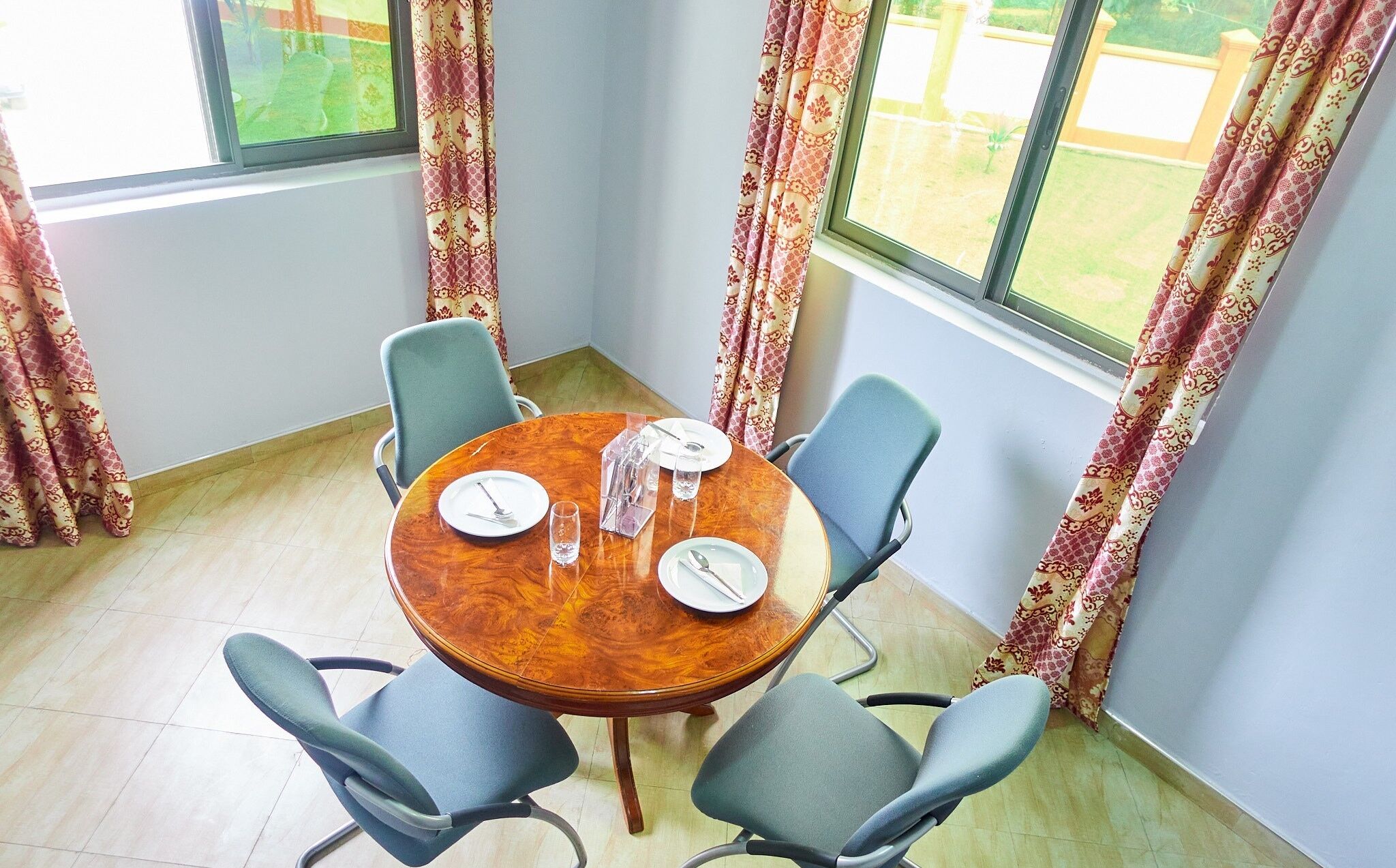 A dining area with a round wooden table, four chairs, and a window with curtains.