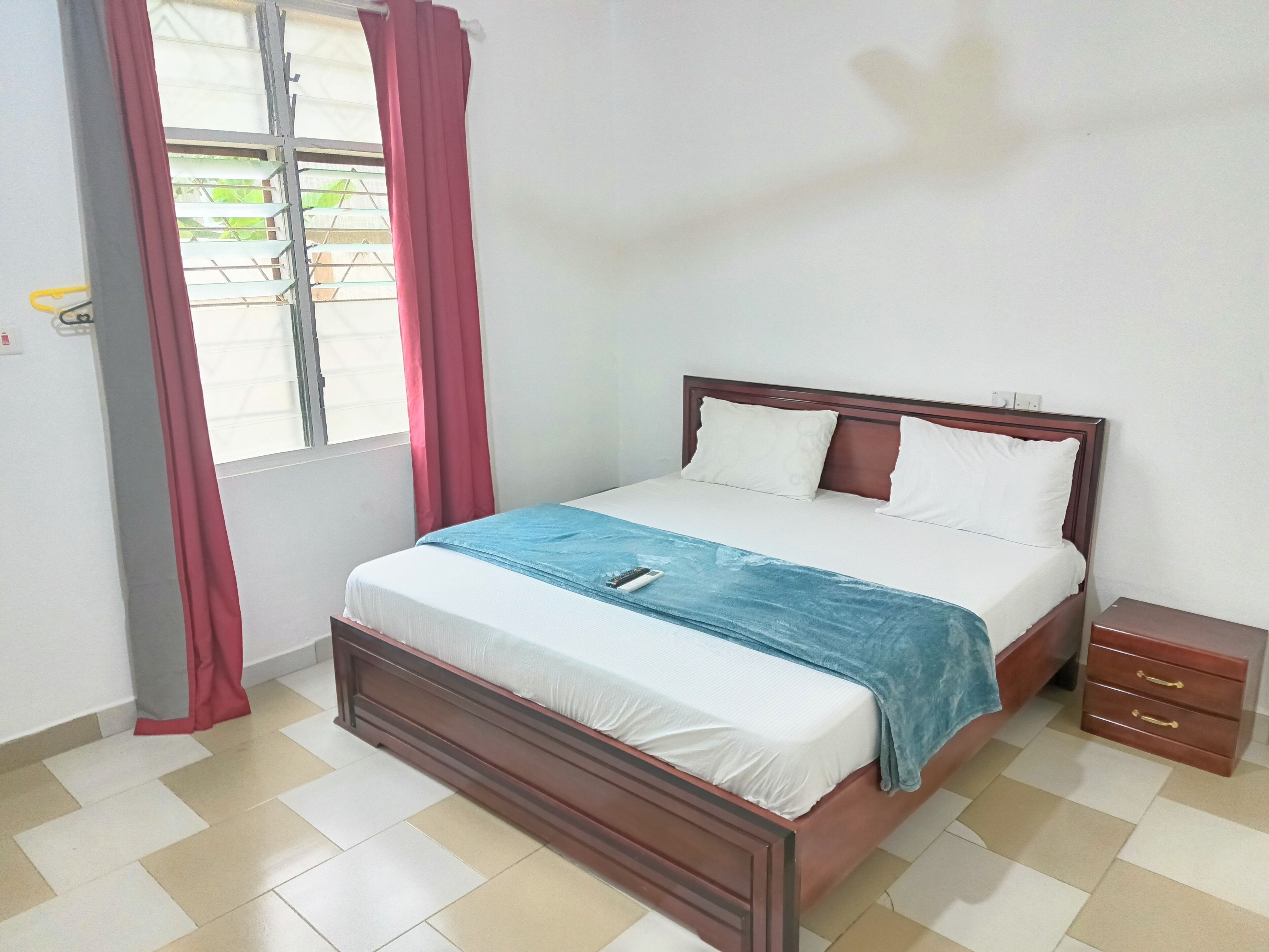 A neatly arranged bedroom with a bed, a bedside table, and a window with curtains.