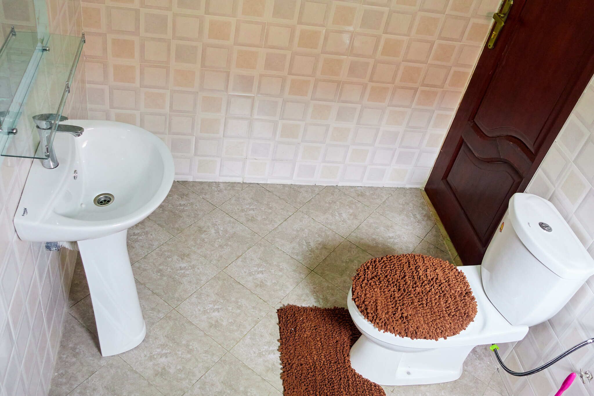 Een badkamer met een wit wastafelmeubel, toilet en betegelde wanden.