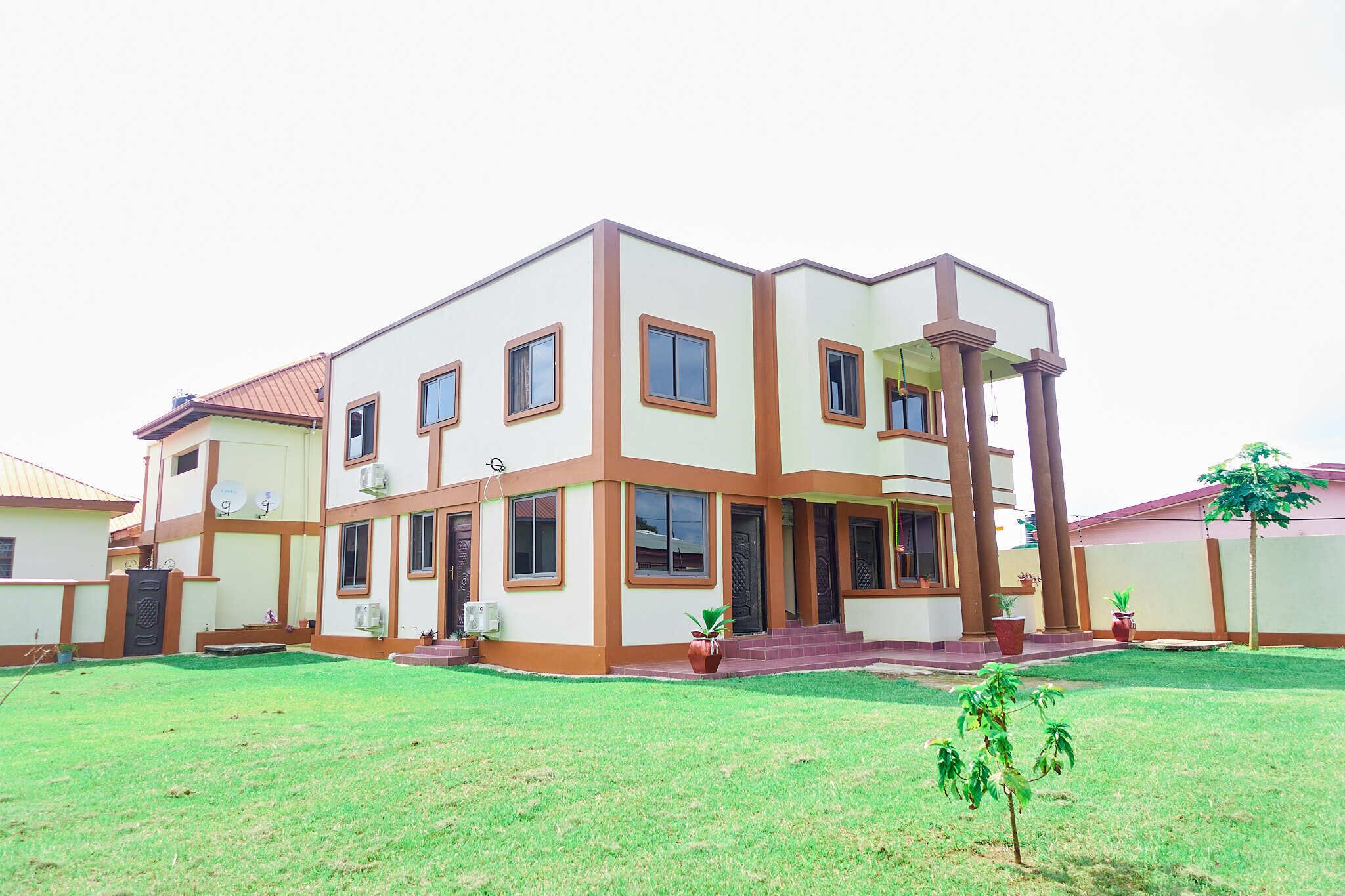 A modern two-story house with a flat roof, multiple windows, and a well-maintained lawn.