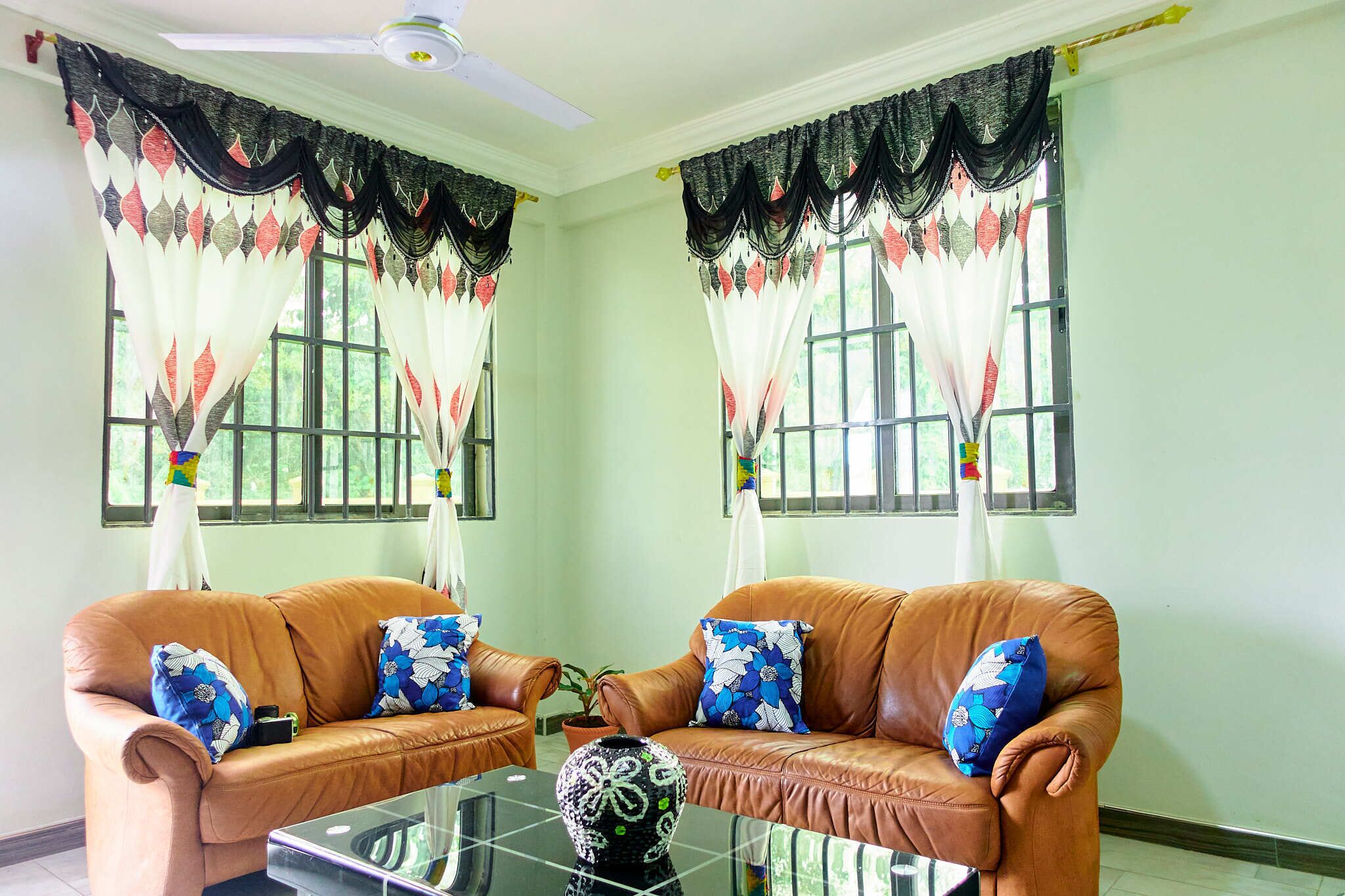 A room with two brown leather sofas, a glass coffee table, and a potted plant.