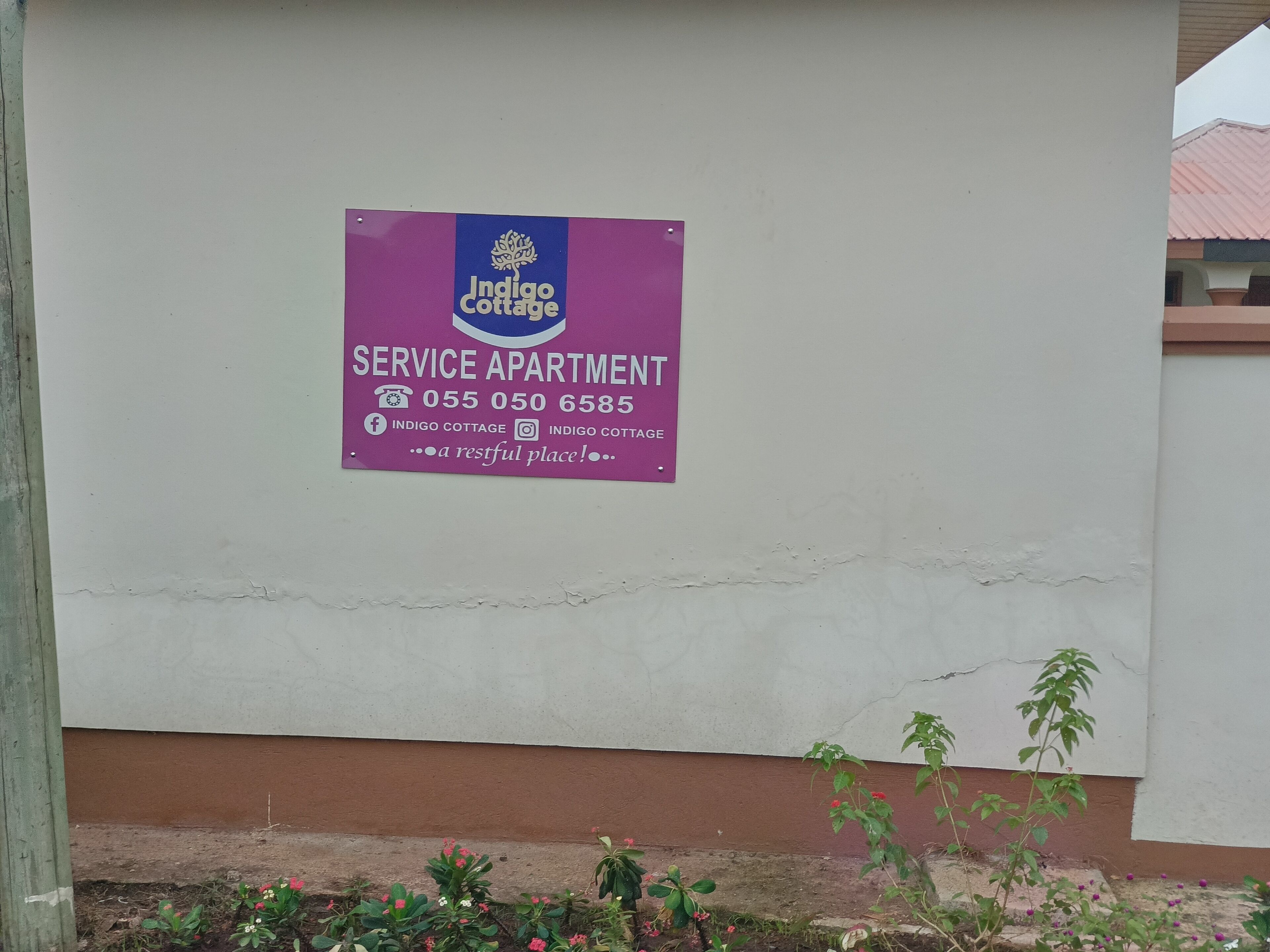 Señal de apartamento con servicios para Indigo Cottage, con información de contacto y perfiles en redes sociales.