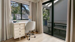 Un dormitorio con un ventanal grande, un escritorio con una silla y una cama.