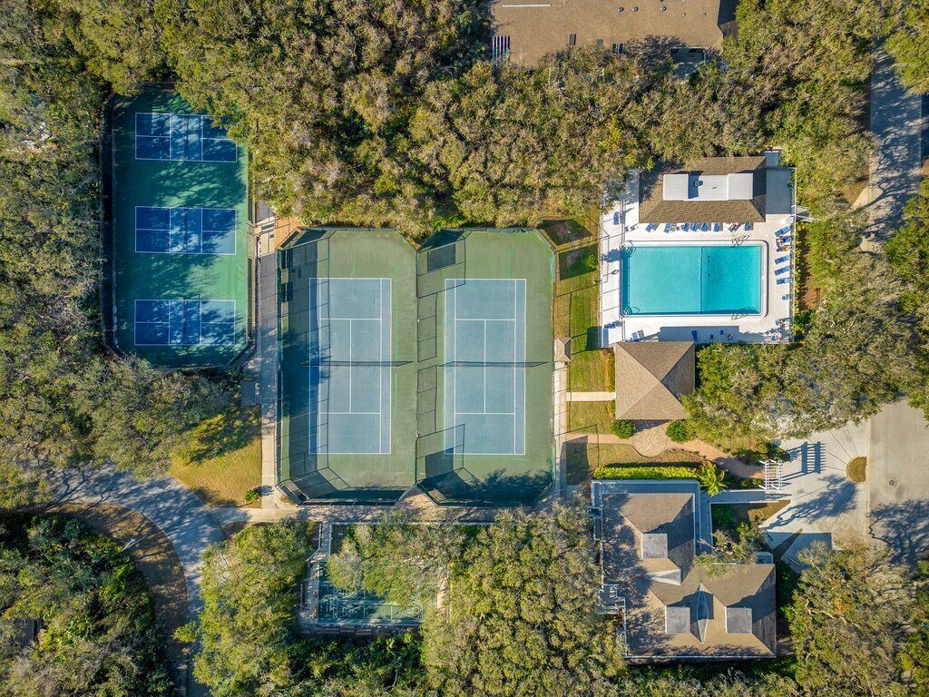 Vista aérea de una propiedad con canchas de tenis, piscina y una casa.