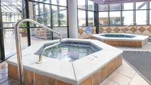 Two hot tubs with metal railings, tiled walls, and a glass enclosure.
