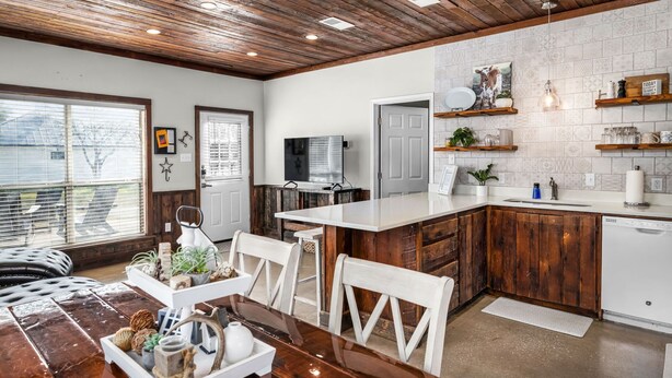 A modern kitchen with wooden cabinets, a white countertop, and a built-in dishwasher. - Riverwalk | Pet-Friendly | Fishing | Deck | Grill (Kyle)