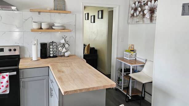 Una cucina moderna con un piano di lavoro in legno, pensili bianchi e una macchina per il caffè.