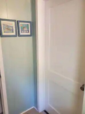 A hallway with light blue walls and a white door. There are two framed pictures on the wall. - Private Single Level Standalone House large lot (Charlotte)