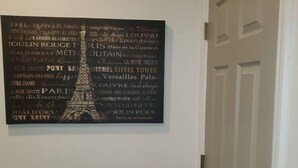 A wall with a black and white poster featuring the Eiffel Tower and various Parisian landmarks. - Entire Studio Apt + Patio + Lake View + Private (Charlotte)