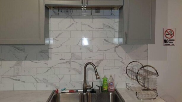 A kitchen with marble backsplash, stainless steel sink, and cabinets. There is a 'No Smoking' sign on the wall. - Entire Studio Apt + Patio + Lake View + Private (Charlotte)