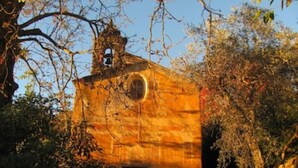 Ein rustikales Gebäude mit einem Glockenturm, umgeben von Bäumen.