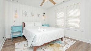 Un dormitorio con cama, ventilador de techo, mesita de noche y decoración en la pared.