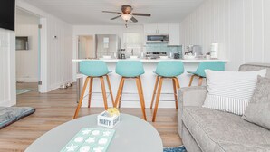 Una cocina moderna con una isla central, taburetes de bar y un comedor.