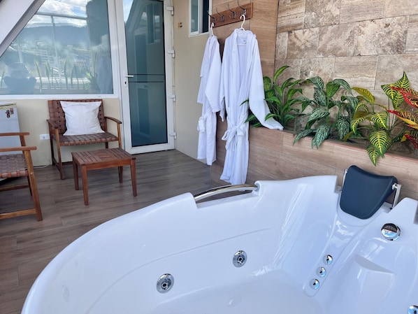 Zona de spa con jacuzzi, mobiliario de madera y plantas en macetas.