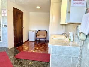 A bathroom with a sink, a mirror, a towel dispenser, and a shower area. - CASA HIDALGO ECUADOR (Cumbayá)