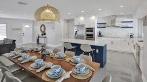 A modern kitchen with white cabinets, a central island, and a dining area with a table set for four.