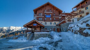 A multi-story hotel with a reception area, balconies, and a stone facade.