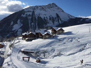 A snow-covered mountain with wooden cabins and a ski lift.