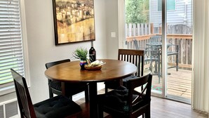 Un coin repas avec une table ronde, des chaises, un tableau et une bouteille de spiritueux.