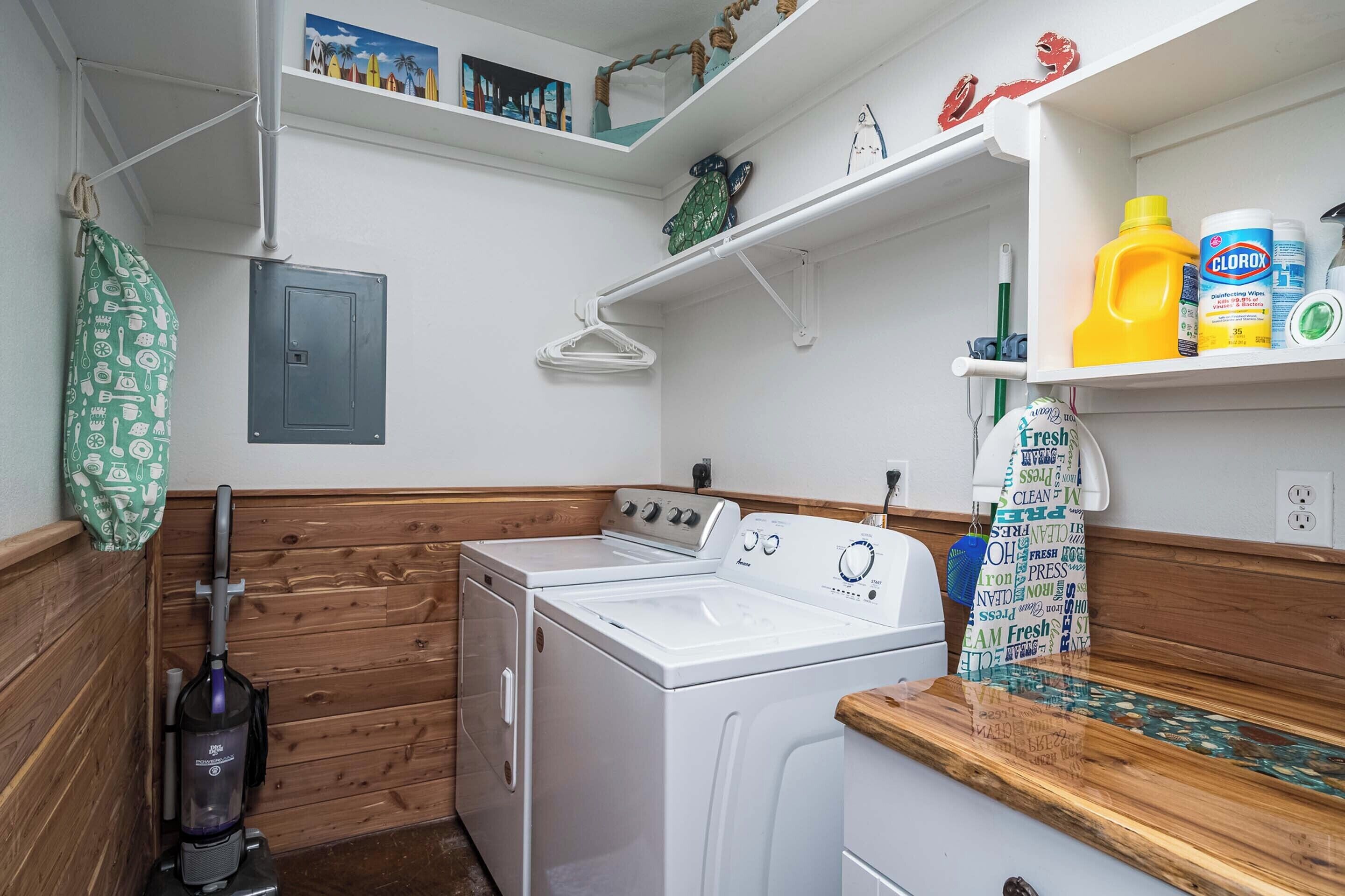 A laundry area with a washing machine, a vacuum cleaner, and shelves with cleaning supplies.