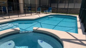 Una piscina amb un banyera d'hidromassatge, envoltada de cadires i una tanca.
